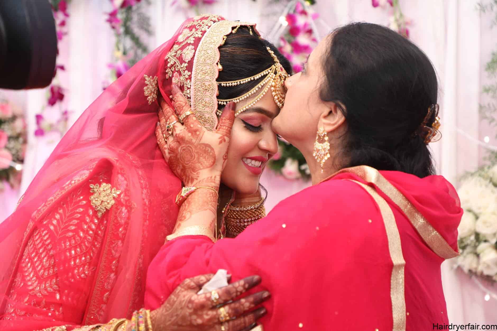 woman in red dress kissing on forehead a woman in wedding dress