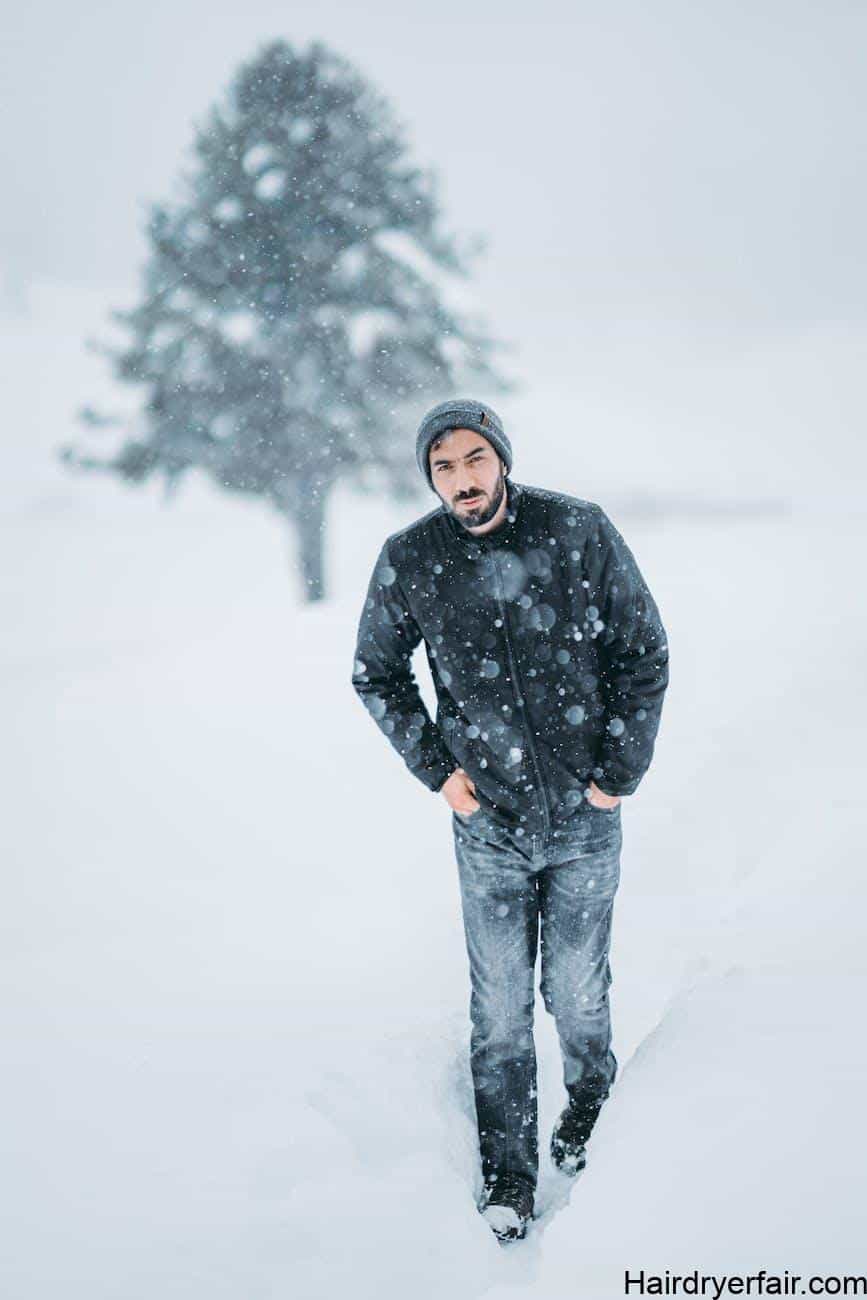man in black jacket standing on snow covered ground